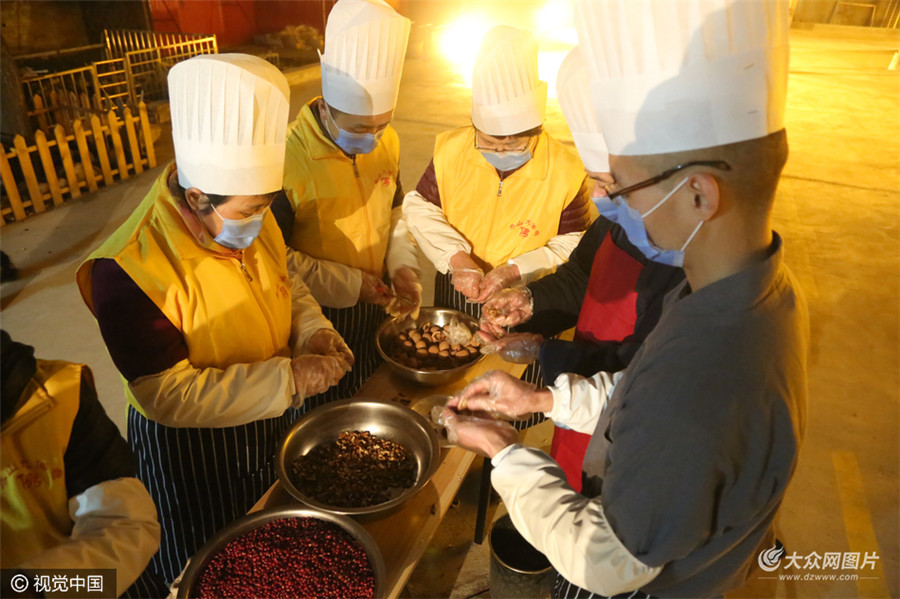 1月4日泰安一座寺庙的师父们借着灯光在寺院内正在加紧熬制传统腊八粥。